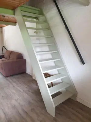a white staircase in a room with a couch at Uniek vakantiehuisje in rustige en groene omgeving in Nieuwe-Niedorp