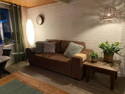 a living room with a brown couch and a table at Uniek vakantiehuisje in rustige en groene omgeving in Nieuwe-Niedorp