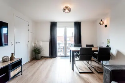 a living room with a dining room table with chairs at Seawave Apartment in Zandvoort