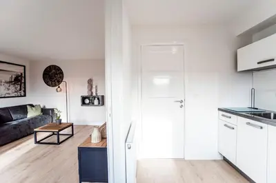 a kitchen and living room with white cabinets at Seawave Apartment in Zandvoort