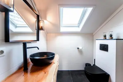 a bathroom with a black sink and a skylight at Seawave Apartment in Zandvoort