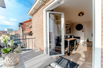 a balcony with a sliding glass door and a table at Seawave Apartment in Zandvoort
