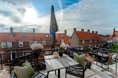 a patio with a table and umbrella on a balcony at Seawave Apartment in Zandvoort