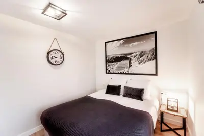 a bedroom with a bed and a clock on the wall at Seawave Apartment in Zandvoort