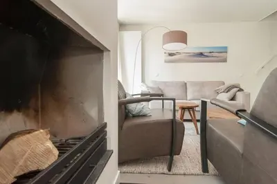 a living room with a fireplace and a couch at Villa Klein Geluk in Egmond aan Zee