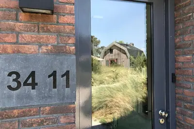 a door with the number on it next to a brick wall at Villa Klein Geluk in Egmond aan Zee