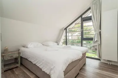 a bedroom with a large bed and a large window at Villa Klein Geluk in Egmond aan Zee