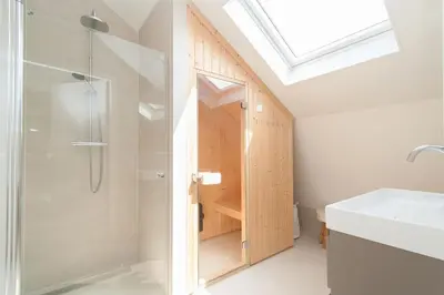 a bathroom with a shower and a sink and a glass shower backdoor at Villa Klein Geluk in Egmond aan Zee