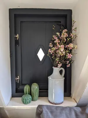 a black door with a vase of flowers on a shelf at StoreStay DamSquare in Amsterdam