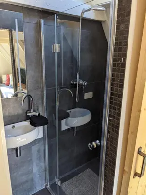 a bathroom with a glass shower with a sink at StoreStay DamSquare in Amsterdam
