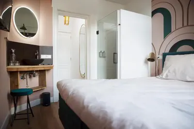 a bedroom with a bed and a sink and a mirror at MUZE Hotel Utrecht in Utrecht