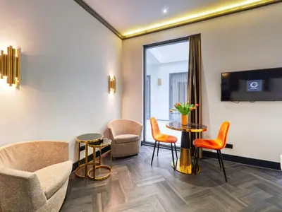 a room with chairs and a table and a tv at Triple G Hotels in Amsterdam