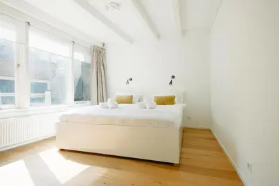 a white bed in a white room with a window at Green Alley Studio in Amsterdam