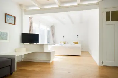 a white living room with a bed and a television at Green Alley Studio in Amsterdam