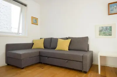 a gray couch with yellow pillows in a living room at Green Alley Studio in Amsterdam