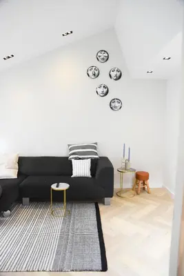 a living room with a black couch against a white wall at In de bocht in Heiloo
