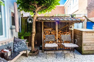 a shed with two chairs and a tree at Het Zomerhuis Family apartment in Zandvoort