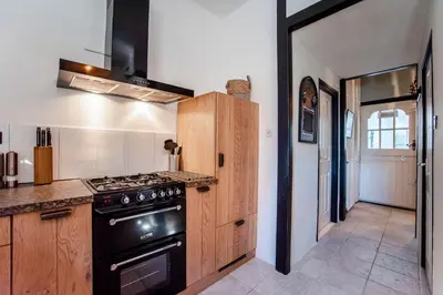 a kitchen with a black stove top oven next to a hallway at Het Zomerhuis Family apartment in Zandvoort