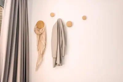 two hooks on a wall with coats and a scarf at The Pine Tree House in Zandvoort