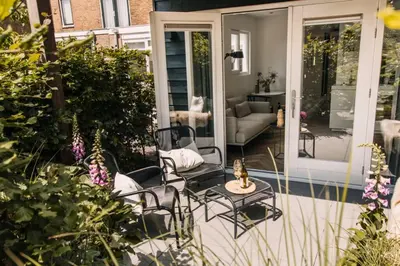 a patio with chairs and a couch on a porch at The Pine Tree House in Zandvoort