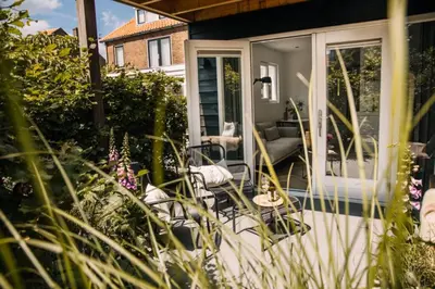 a screened in porch with chairs and a couch at The Pine Tree House in Zandvoort