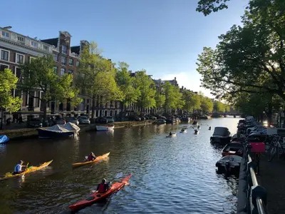 a group of people kayaking down a river in canoes at KG House in Amsterdam