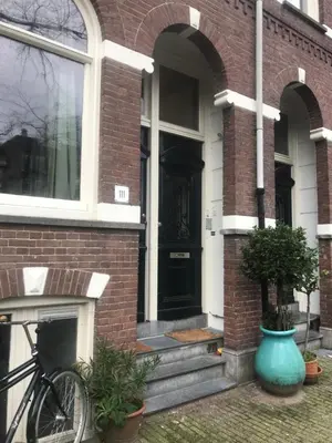 a bike parked outside of a brick house with a black door at Six in Amsterdam