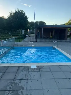 a large blue swimming pool in front of a building at Vakantiehuis Villa Zeewolde in Zeewolde