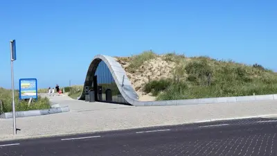 a bridge over a road next to a hill at Emma's beach house in Katwijk aan Zee