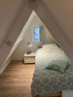 a attic bedroom with a bed and a window at Dromen aan het strand in Egmond aan Zee
