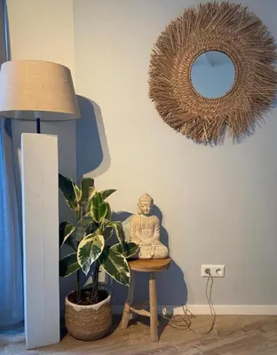 a statue sitting on a chair in a room with a mirror at Dromen aan het strand in Egmond aan Zee