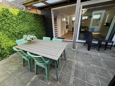 a wooden table and chairs on a patio at Beaufort in Egmond aan Zee