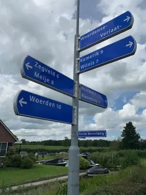 a street sign with blue signs on a pole at Froukje's B&B in Woerdense Verlaat
