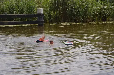 two children swimming in a pond with a boogie board at Froukje's B&B in Woerdense Verlaat
