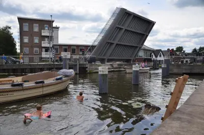 two people swimming in the water next to a boat at Froukje's B&B in Woerdense Verlaat