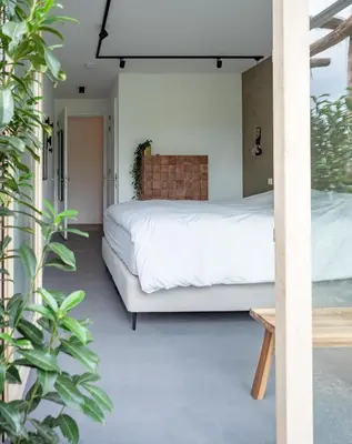 a bedroom with a bed in a room with plants at Onze Kas in Lelystad