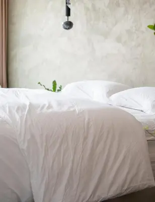 a white bed with white sheets and pillows at Onze Kas in Lelystad