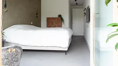 a bedroom with a white bed and a television at Onze Kas in Lelystad