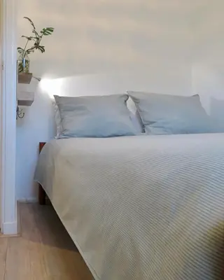 a bed with blue pillows in a bedroom at Sea shell with balcony close to the beach, city centre and dunes in Zandvoort