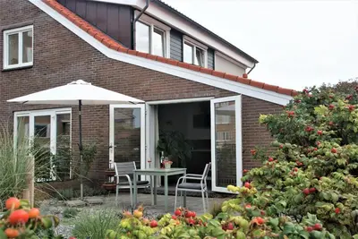 a house with a table and chairs and an umbrella at Huis Zeeduin Amsterdam Beach in Zandvoort
