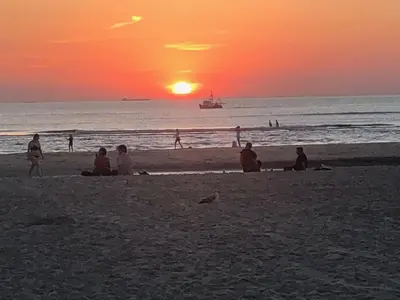 a group of people sitting on the beach at sunset at Huis Zeeduin Amsterdam Beach in Zandvoort