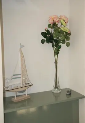 a vase of flowers on a table with a boat at Huis Zeeduin Amsterdam Beach in Zandvoort