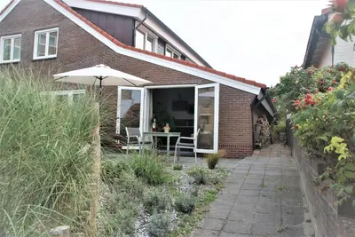a house with an umbrella and a table and chairs at Huis Zeeduin Amsterdam Beach in Zandvoort