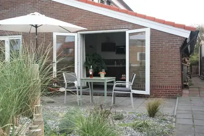 a patio with a table and chairs and an umbrella at Huis Zeeduin Amsterdam Beach in Zandvoort