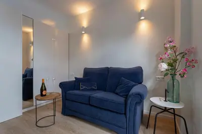 a blue couch in a living room with a vase of flowers at Studio Baarn with patio, airco, pantry, bedroom, bathroom, privacy - Amsterdam, Utrecht in Baarn