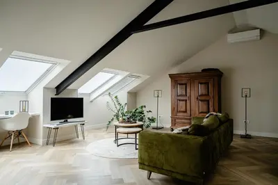 a living room with a green couch and a tv at B&B de Cley in Noordwijk