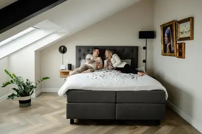 two people sitting on a bed in a room at B&B de Cley in Noordwijk