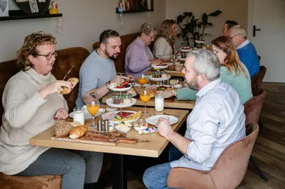 a group of people sitting at a table eating food at B&B de Cley in Noordwijk