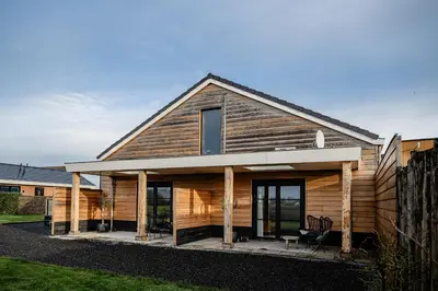 a wooden house with a front porch and windows at B&B de Cley in Noordwijk