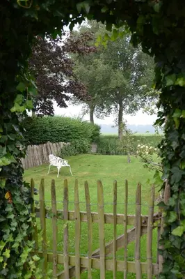 a statue of a cow in a field behind a fence at Apartment Het Friesche Paard in Purmer